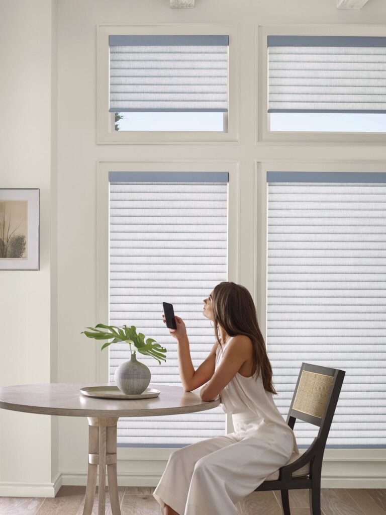 Smartphone controlling automated Sonnette roller shades by Hunter Douglas in a home
